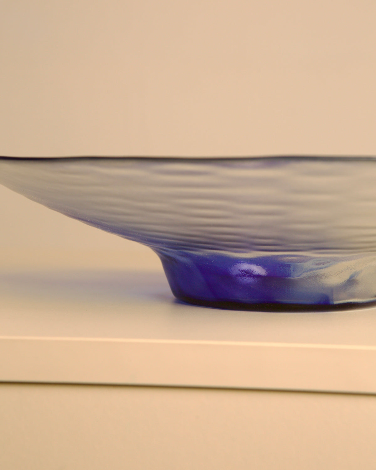Large 80s Italian circular dish in transparent and blue wavy glass — side angle