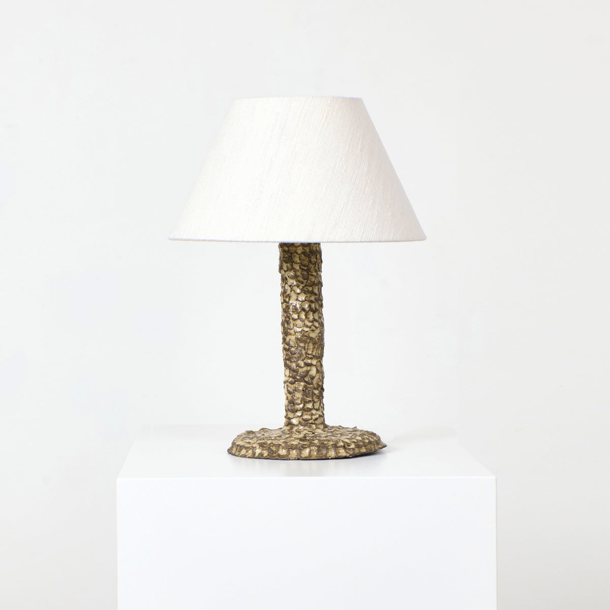 Casa Bedside Light — angled view on white pedestal with textured base