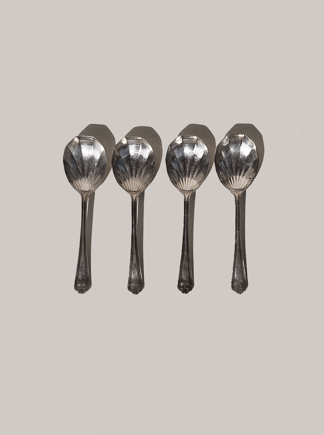 Four silver-plated dessert spoons with decorative shell bowls