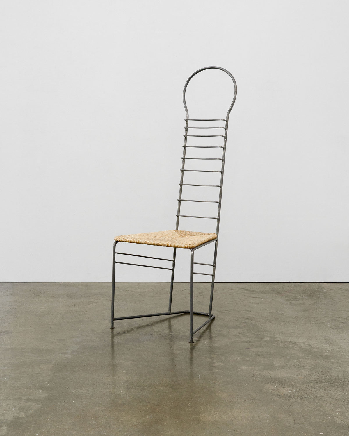 Sculptural steel chair with woven straw seat and tall ladder-back