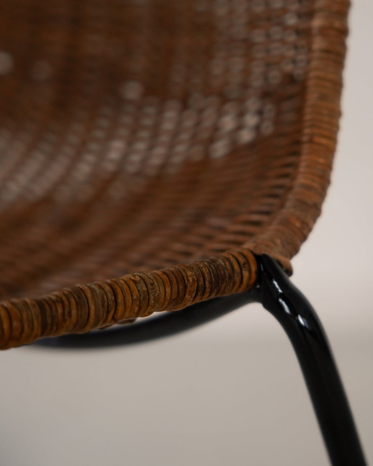 Woven rattan detail and black metal frame of Basket Chair