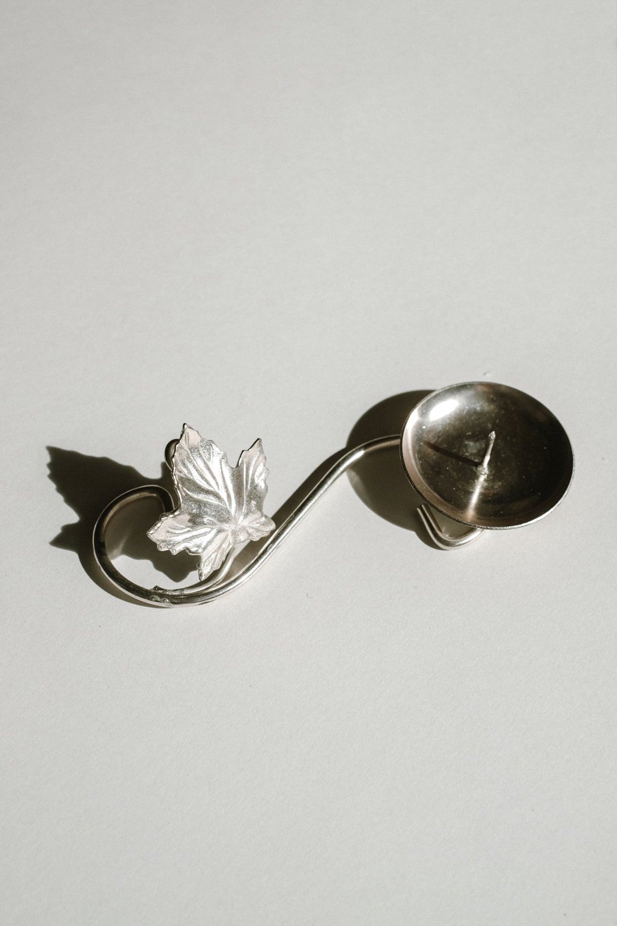 Silver-plated candle holder with maple leaf detail and curved handle