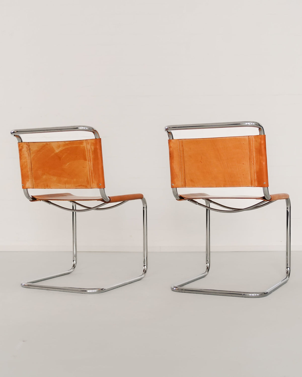 Two B33 cantilever chairs by Marcel Breuer with orange leather seats