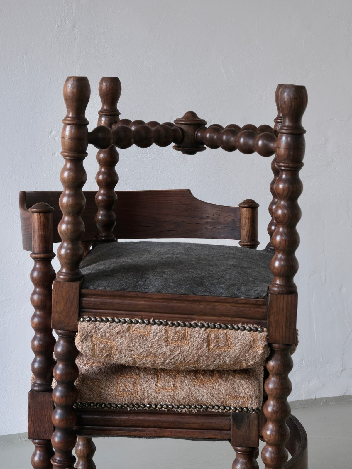 Antique bobbin turned corner chair with dark wood frame and leather seat