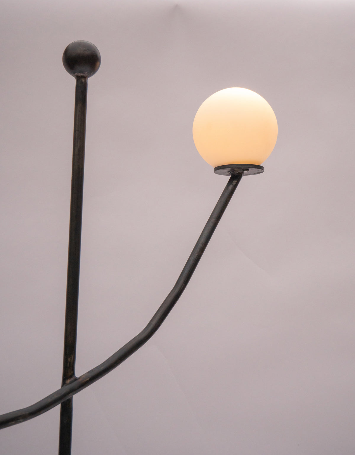 Balancing Act floor lamp with illuminated sphere and curved black arm