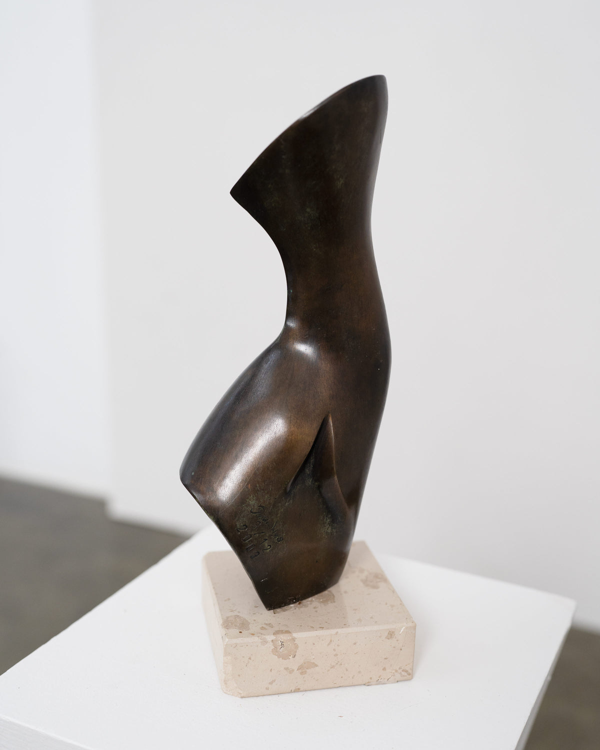 Abstract bronze sculpture with curved angular form on stone base by Stanislaw Wysocki