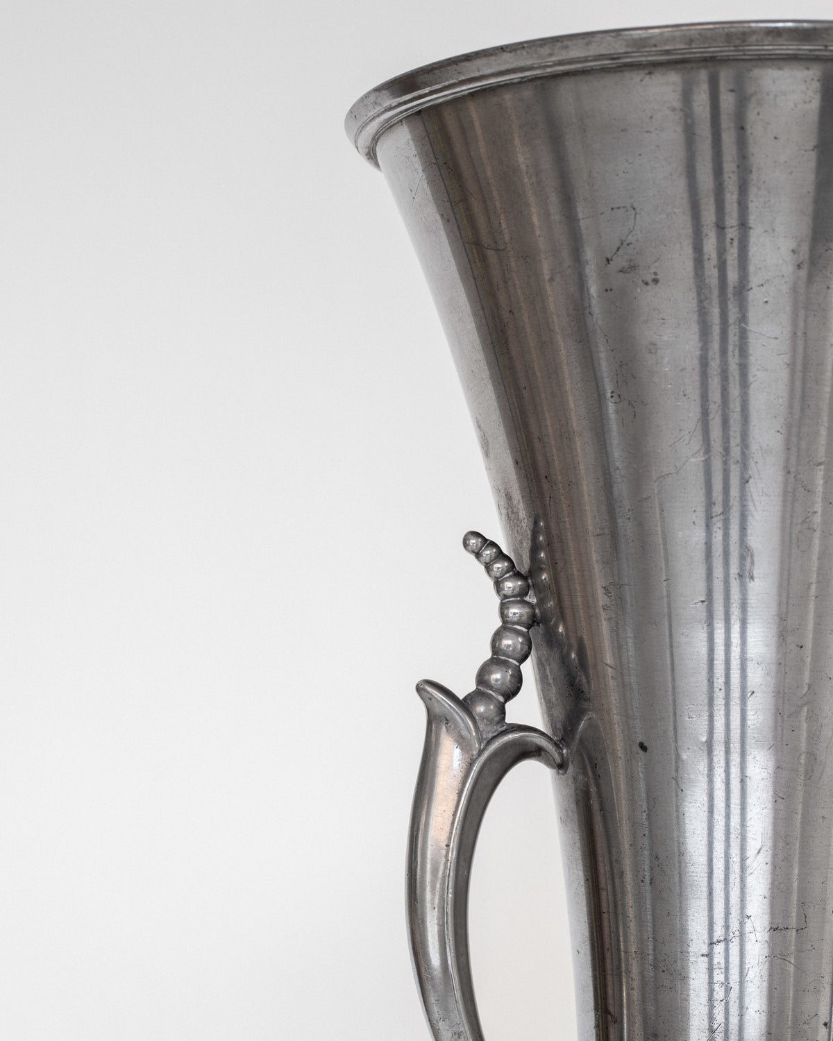 Close-up detail of Art Deco pewter vase handle with beaded design
