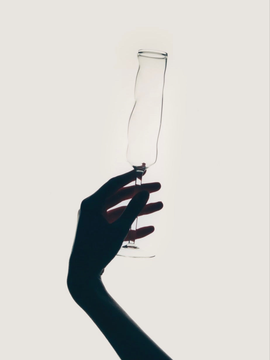 Hand holding elegant champagne coupe against minimalist background