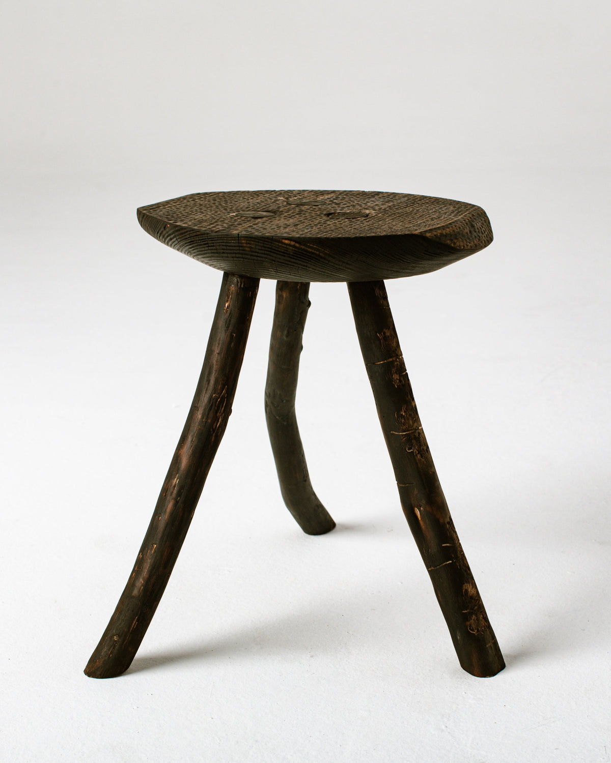 Handcrafted burned wood stool with natural branch legs detail