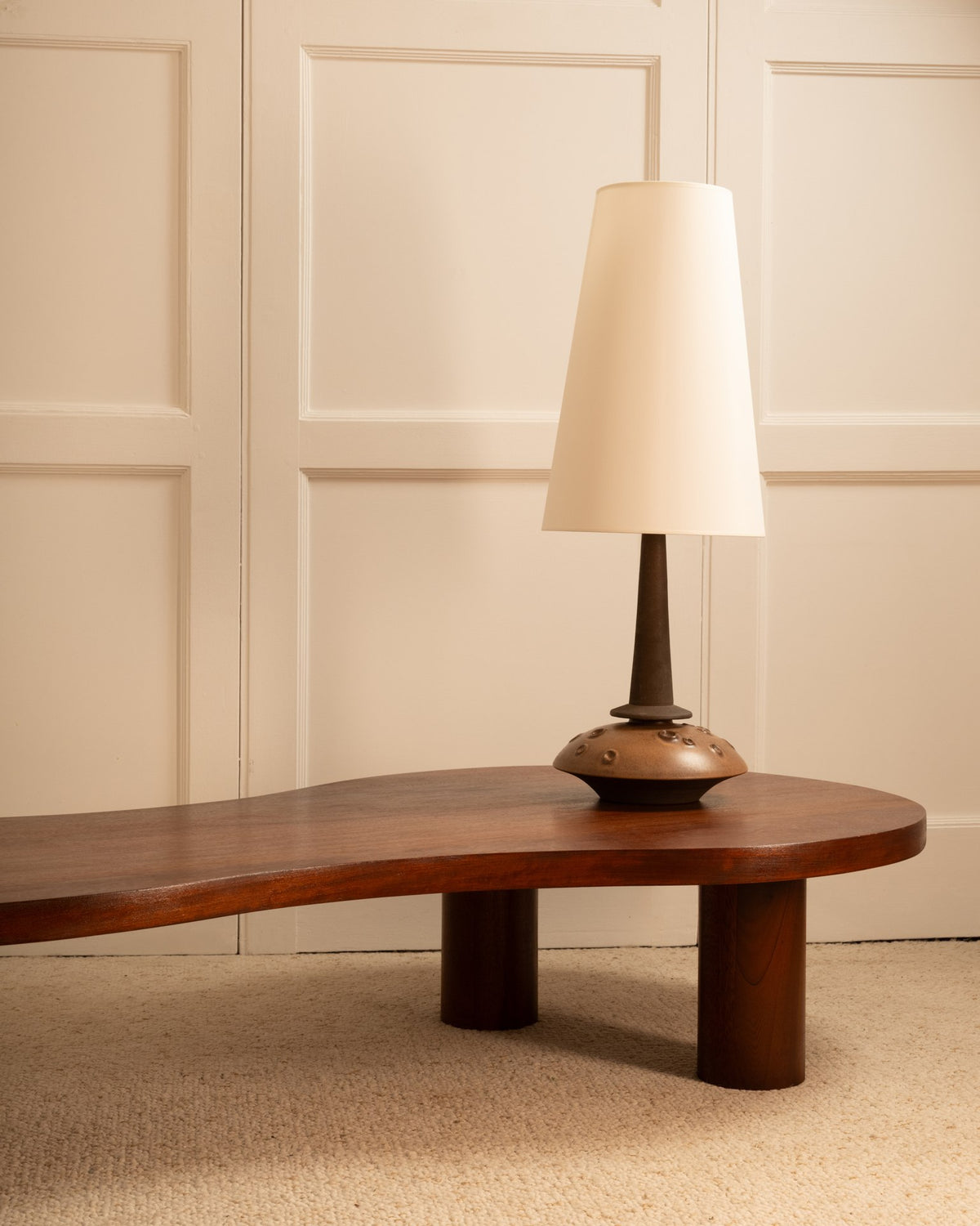 Danish ceramic table lamp with white shade on walnut coffee table