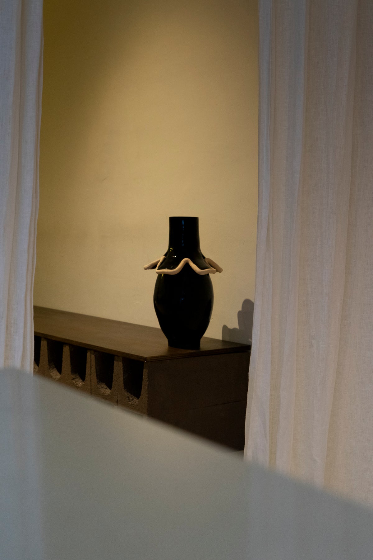 Navy blue ceramic vase with white ruffled collar, lifestyle setting