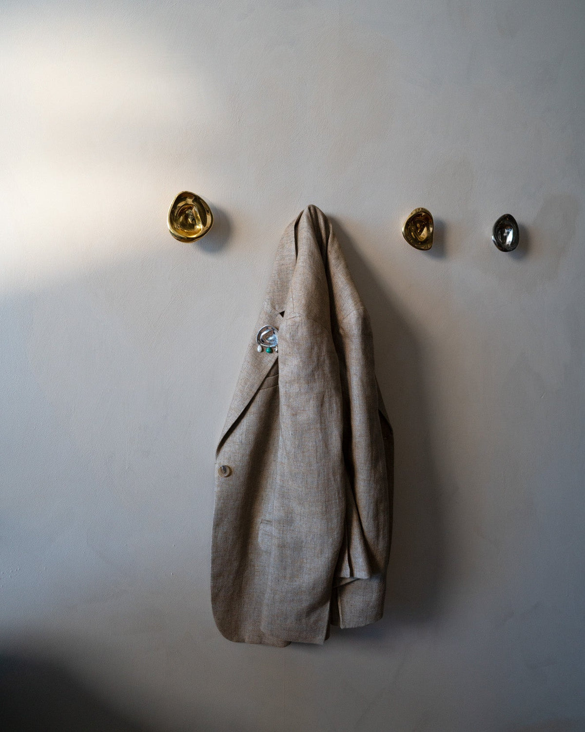 Ripple Hook - Small - Titanium — top view with beige jacket hanging on wall