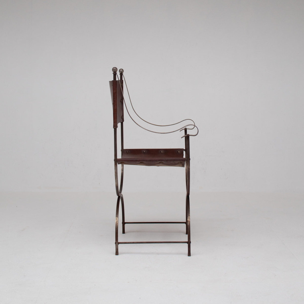 French pair of Iron Curule Chairs in Leather — back view highlighting leather seat and iron frame