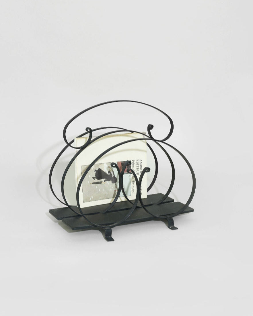 Black iron magazine rack with curved metal frame on rectangular base