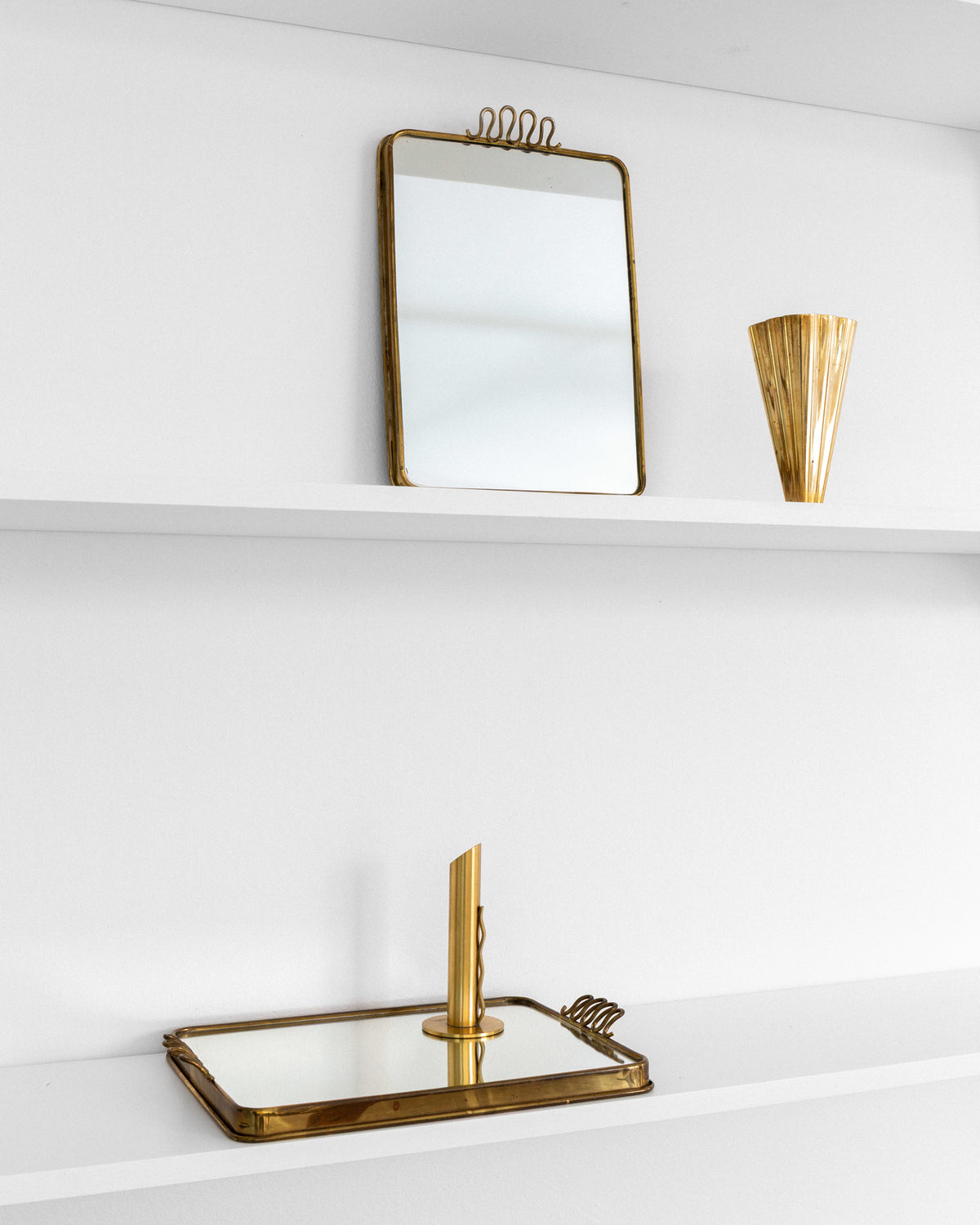 Pair of Scandinavian Modern Brass Mirrored Trays, 1950s–60s — side angle on white shelf with decorative items
