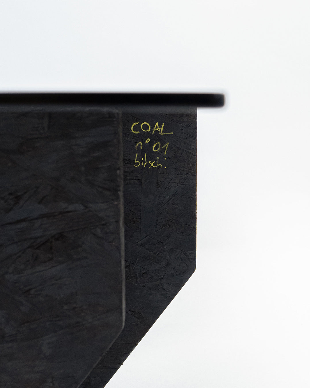 Close-up detail of Coal coffee table's textured black surface and edge