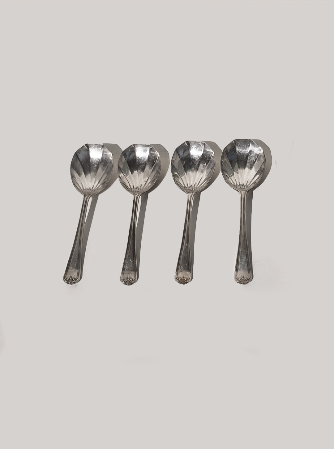 Four silver-plated shell spoons arranged in row showing bowl detail