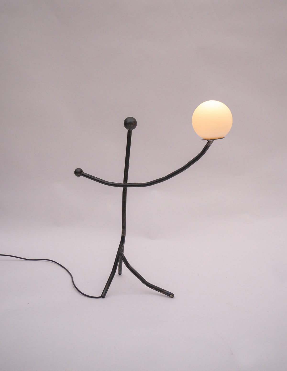 Balancing Act table lamp with illuminated sphere on black metal figure