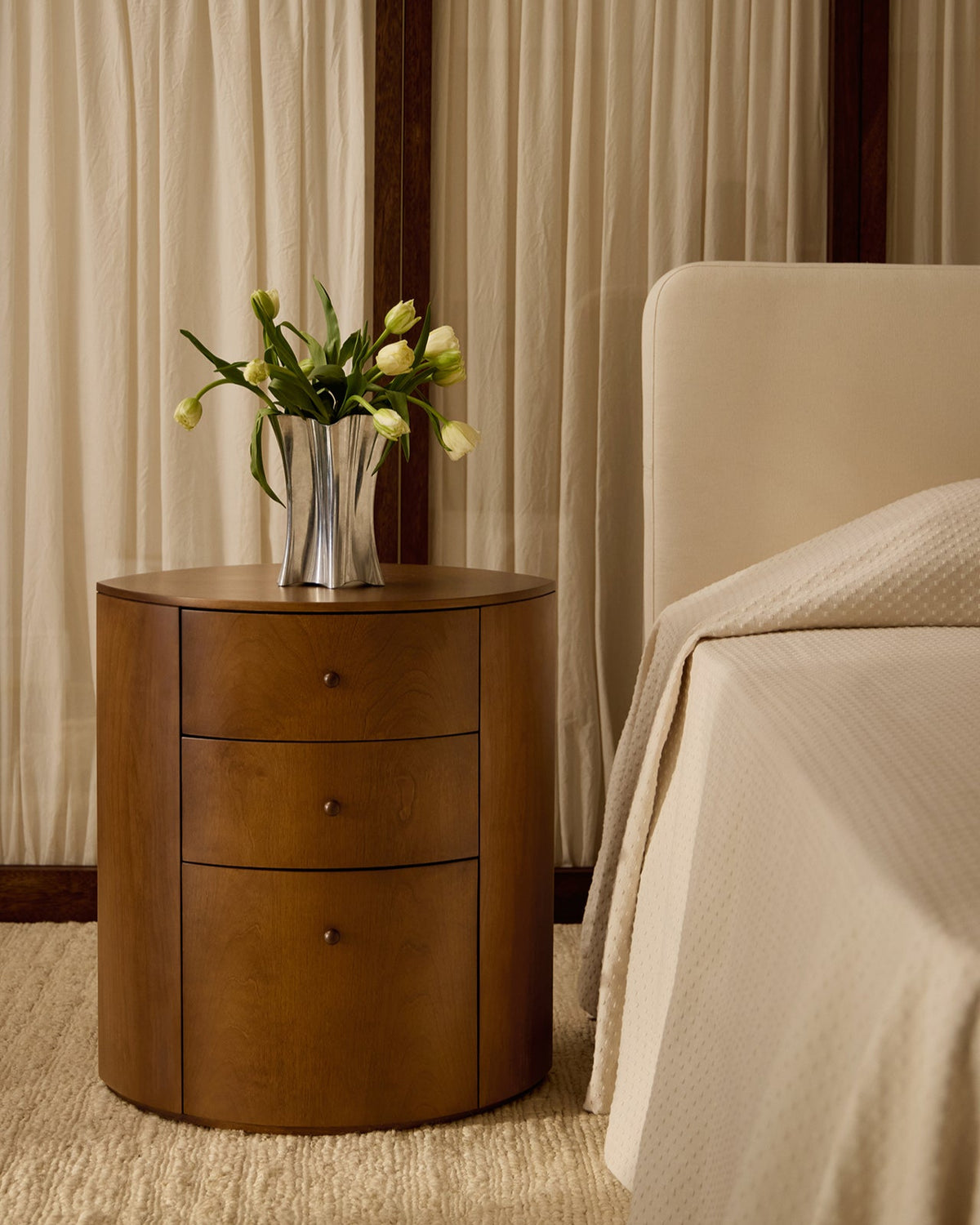 Observer nightstand in warm brown birch with three drawers beside bed