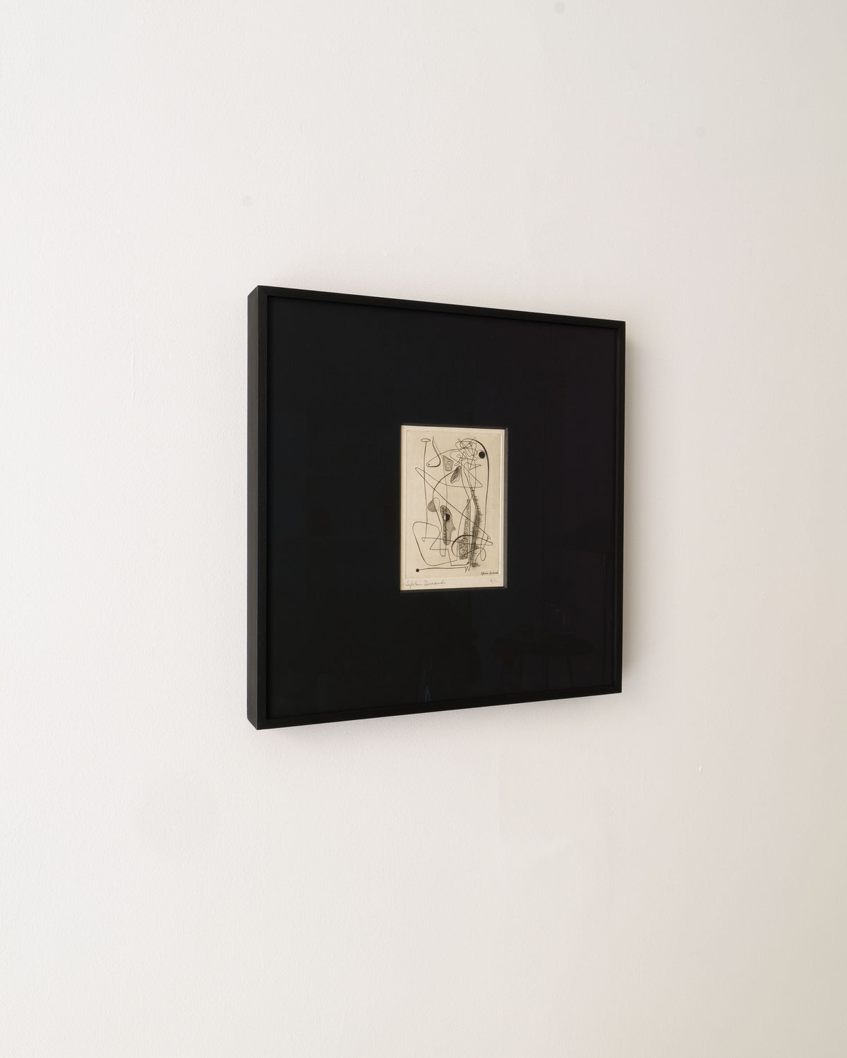 A signed Surrealist Engraving by Sylvain Durand from Collection apart, featuring minimalistic overlapping lines in a black frame, centers on a plain white wall as an abstract figure.