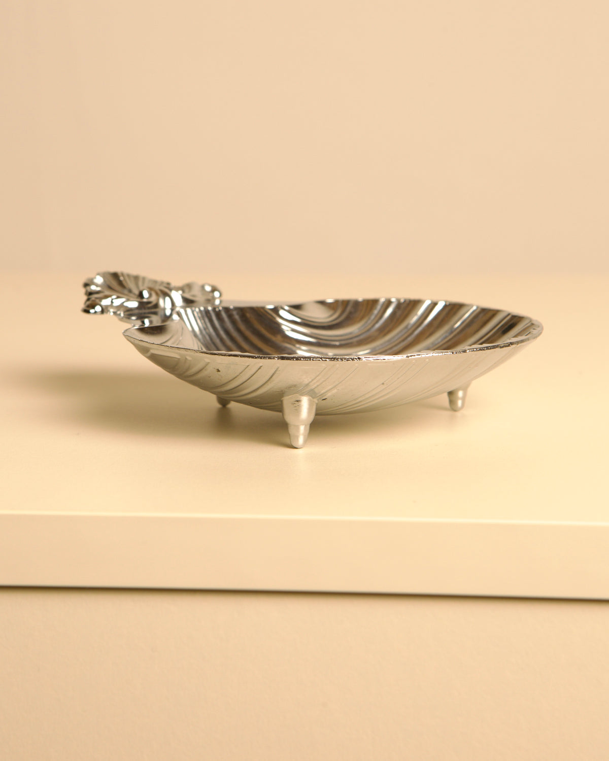 Silver-plated shell dish with decorative handle and three legs
