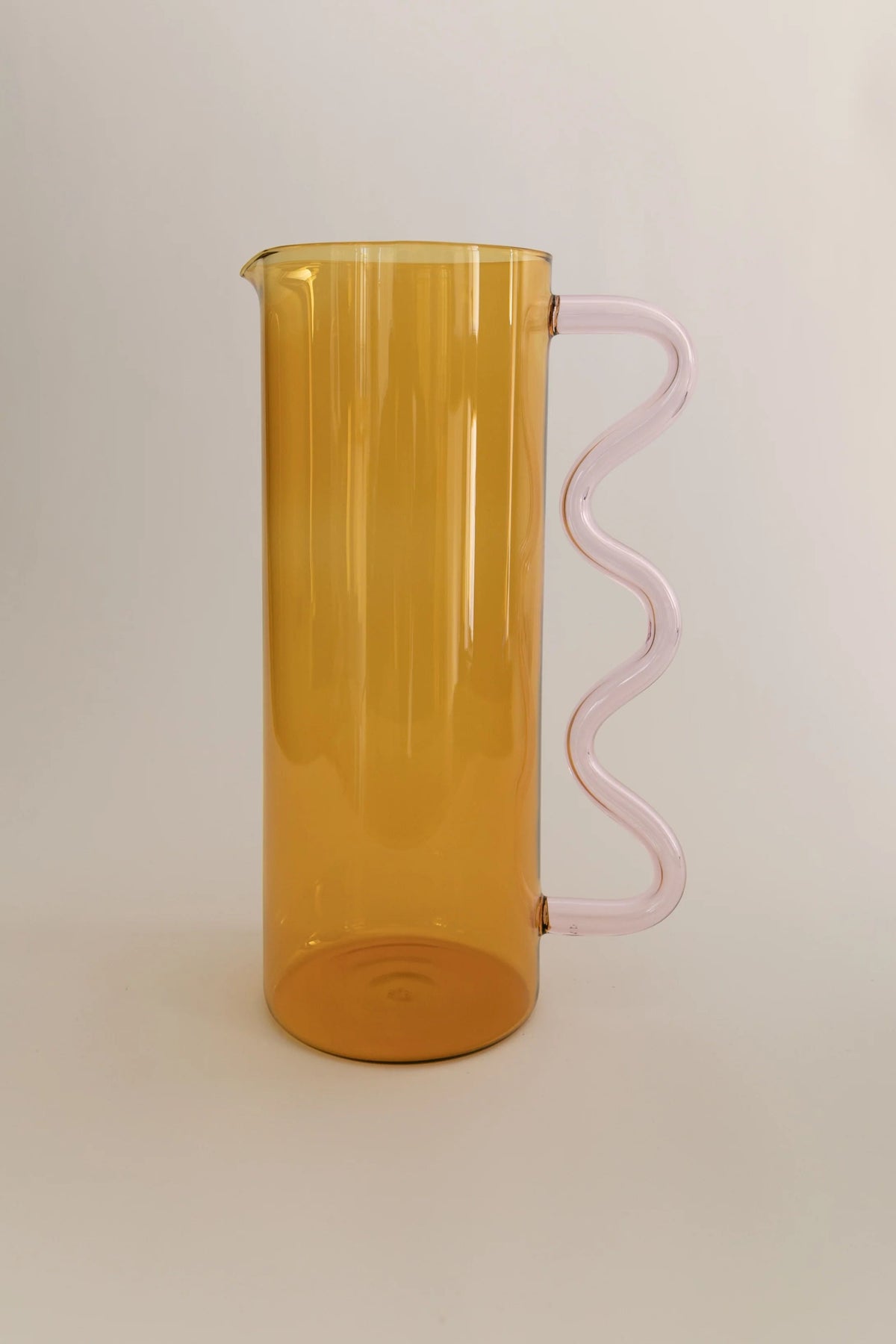 Wave Pitcher — side view of amber glass with pink handle