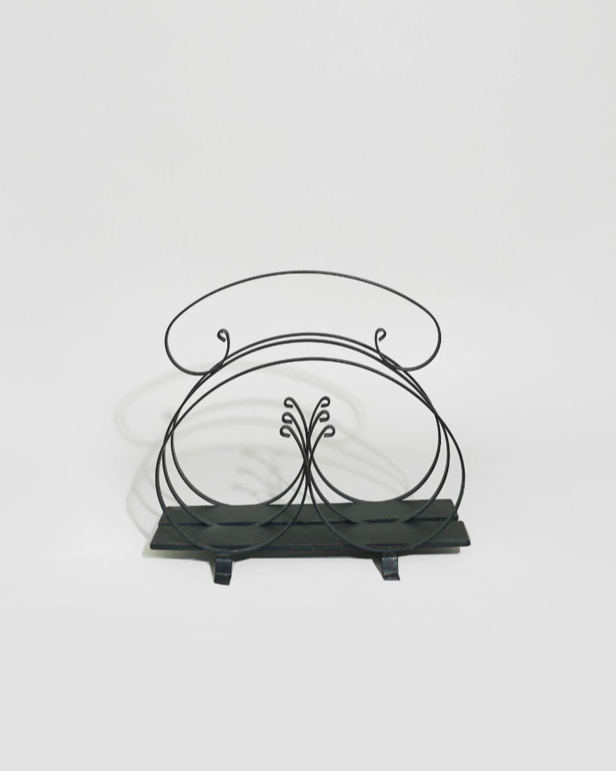 Elegant black iron magazine rack with decorative scrollwork design