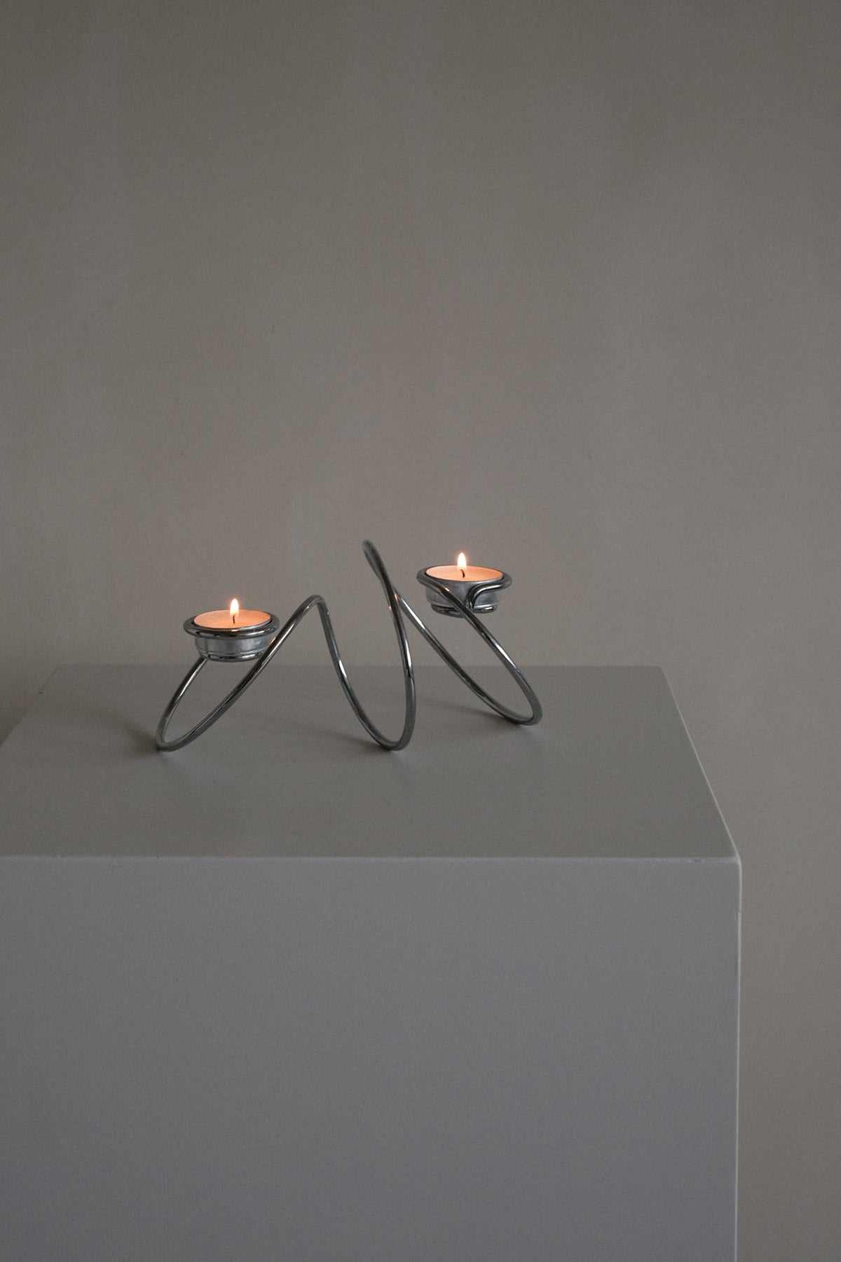 Chrome Candleholder — top view on minimalist pedestal with candles lit