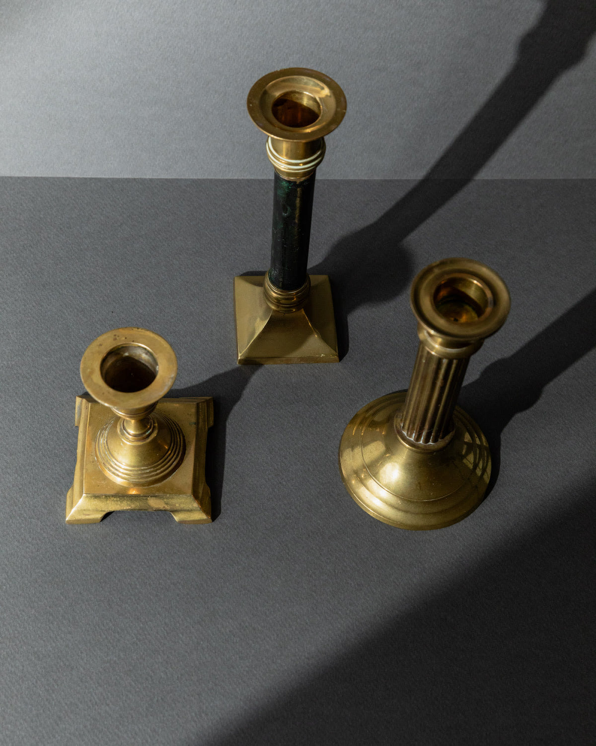 Vintage 1940s Brass Candleholders Set of 3, Mixed Shapes, Classic Antique Design — top view on gray background