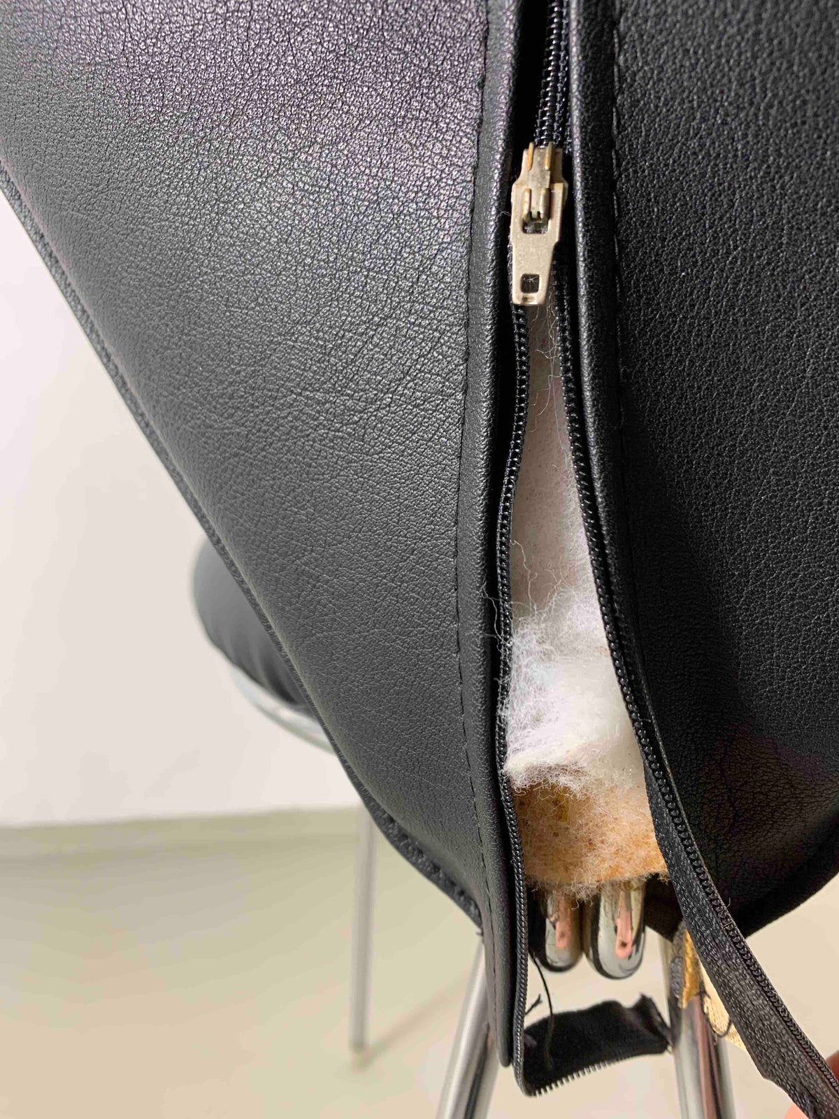 Close-up detail of black leatherette upholstery zipper on Lubke chair