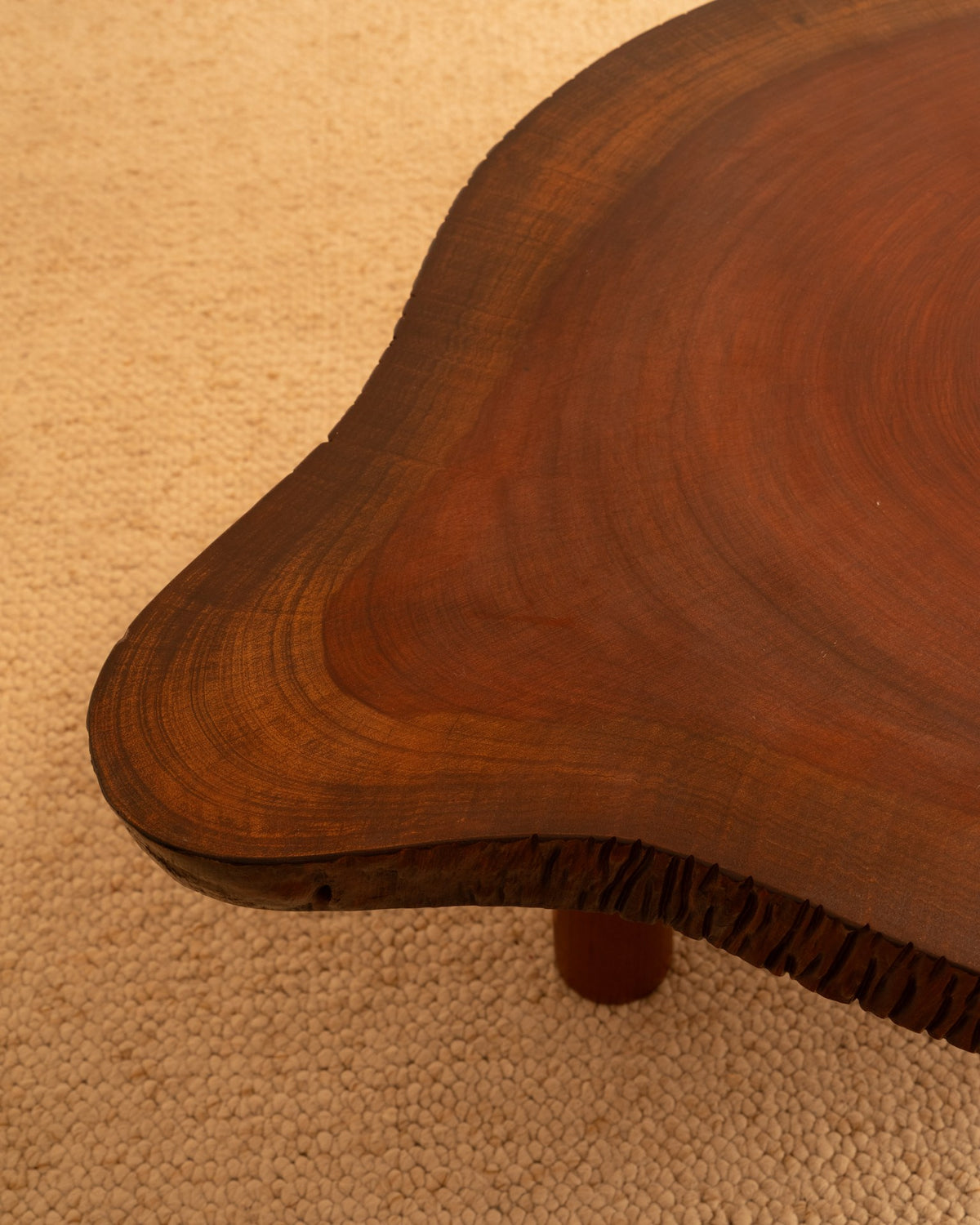 Curved wooden drop-leaf table detail showing rich grain pattern