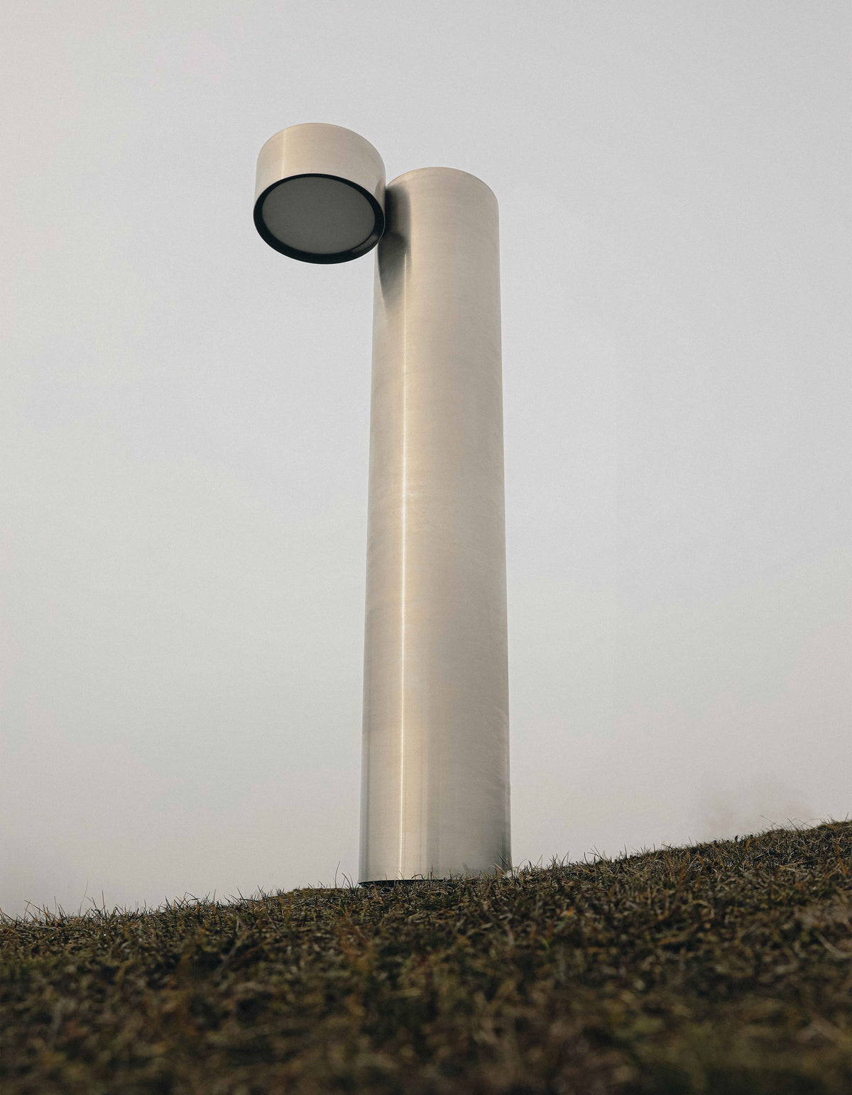 X floor lamp — close-up of polished metal finish against grass