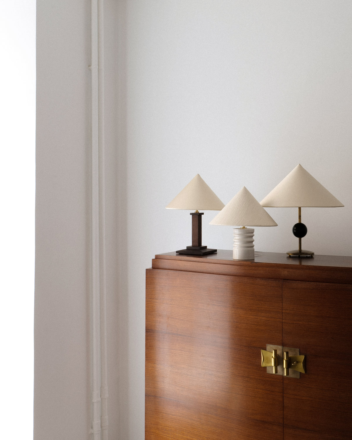 Three conical shade table lamps styled on walnut credenza with brass hardware