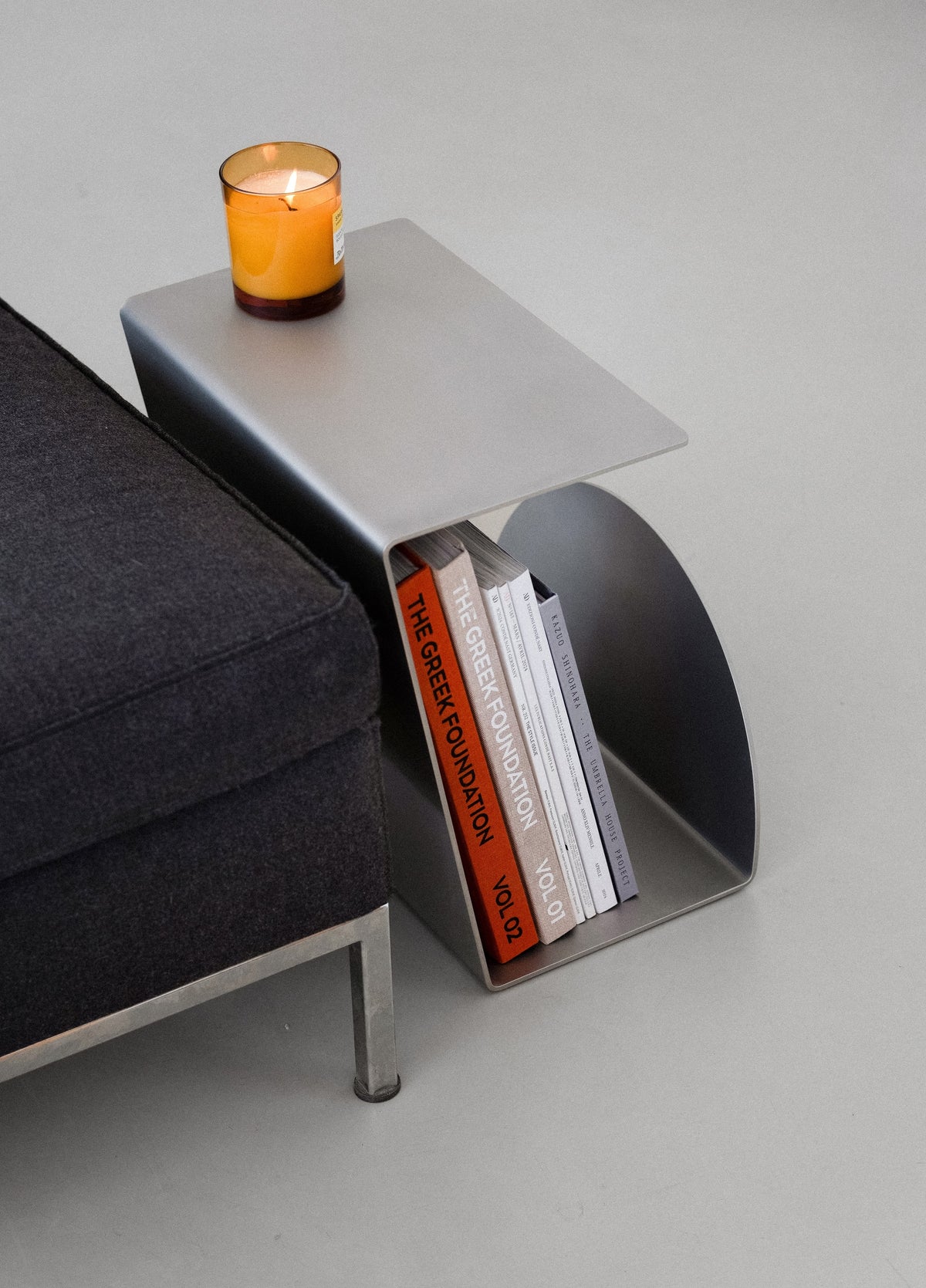 Side Table - 1.0 - Stainless Steel — angled view with books and candle