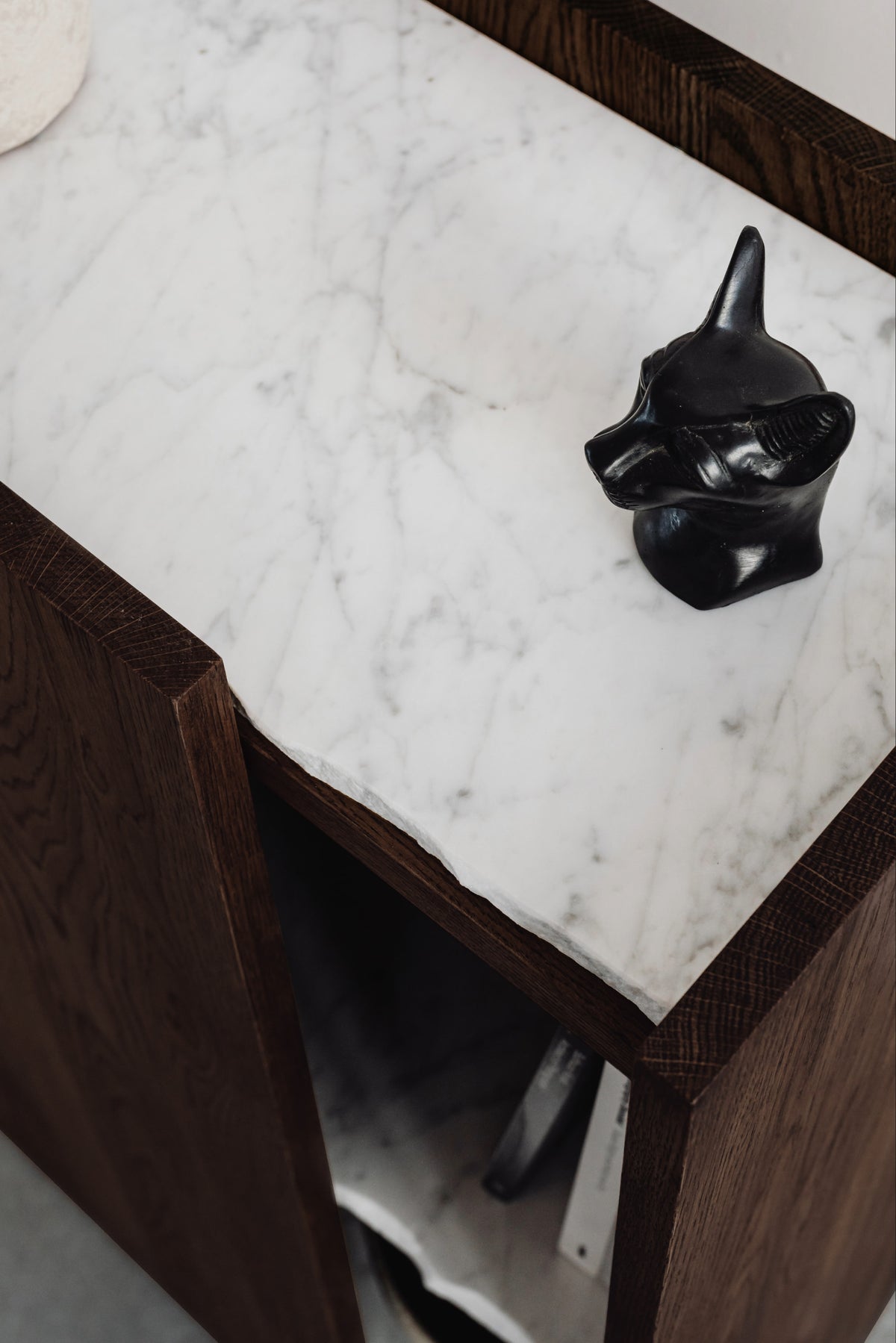 PAVO cabinet detail showing marble top with black decorative object on walnut wood frame