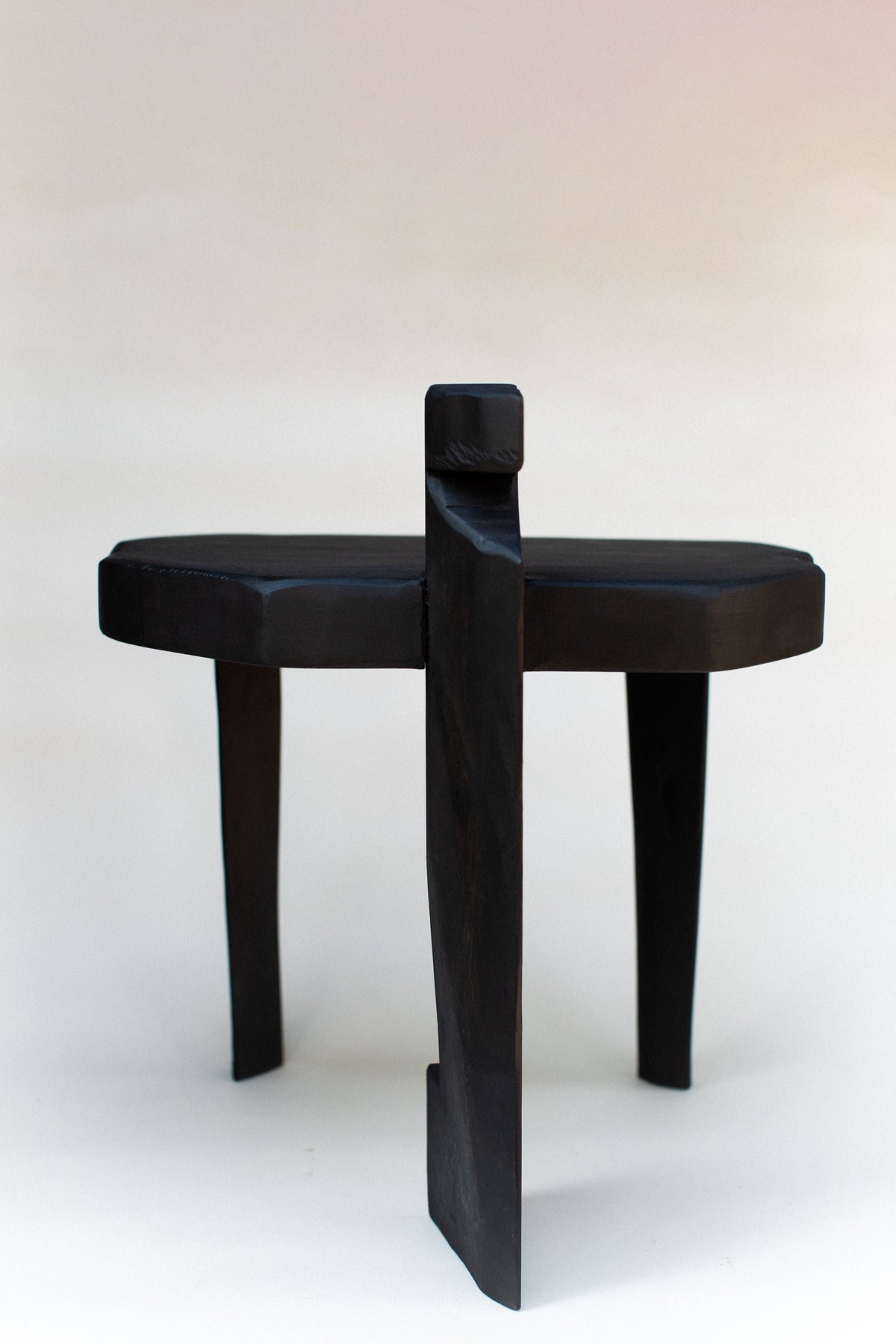 Black wooden stool with round seat and distinctive vertical back support
