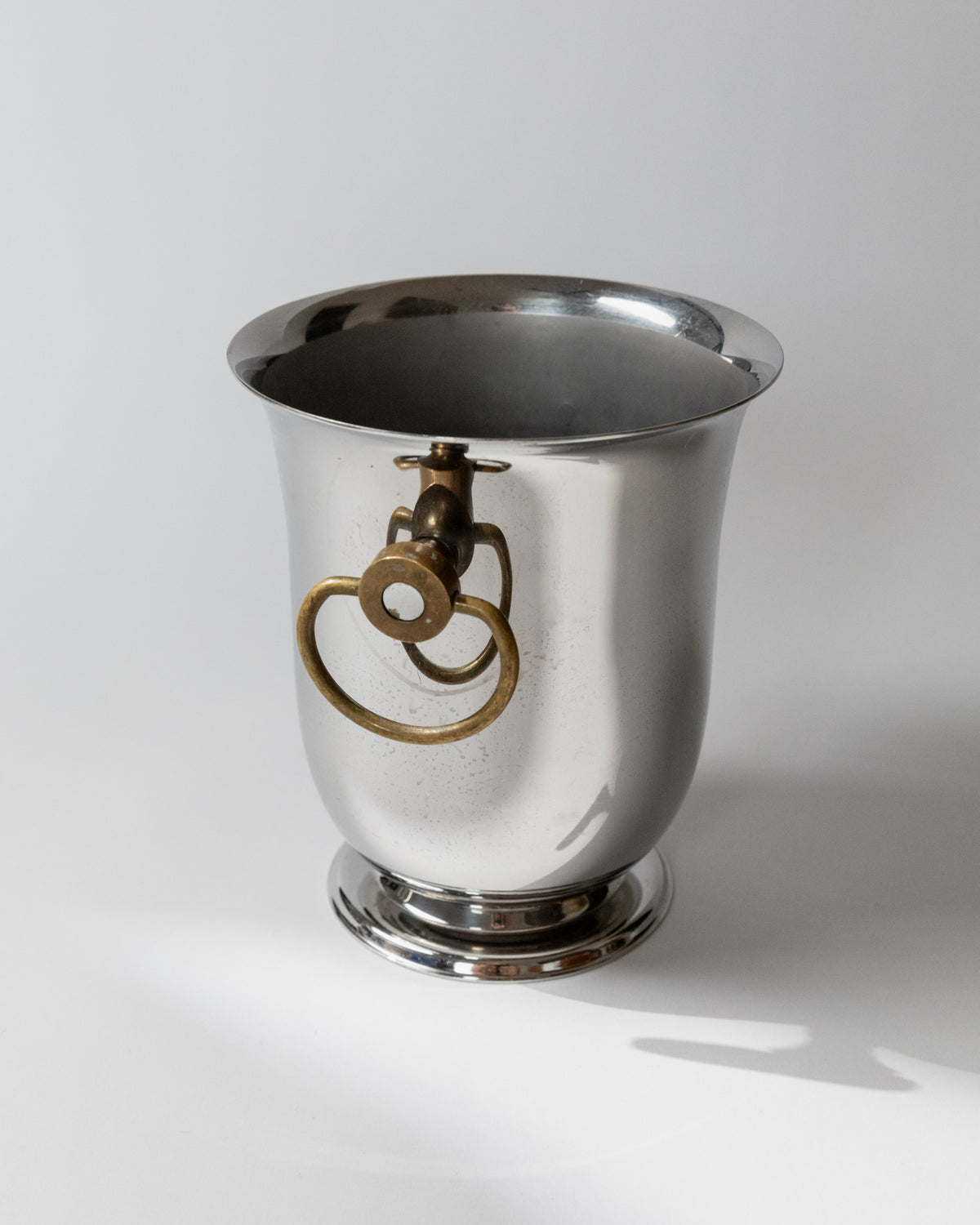Polished steel wine cooler with brass ring handles by Jean Couzon