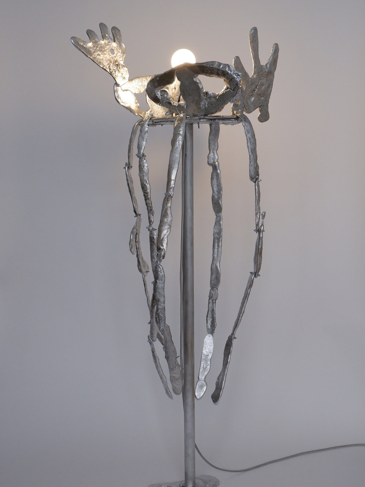 Sculptural bronze floor lamp with organic metallic forms and illuminated bulb