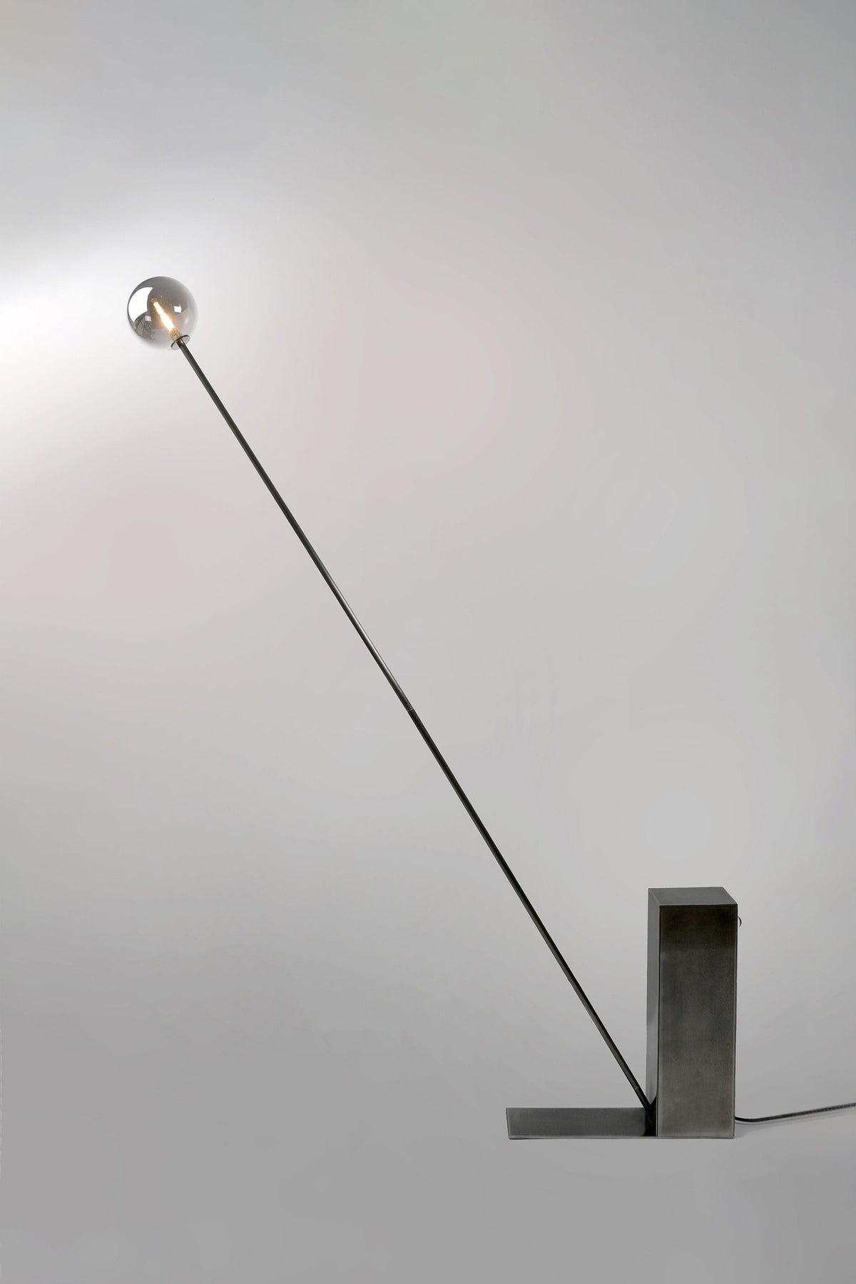 Modern steel floor lamp with angled arm and spherical glass shade