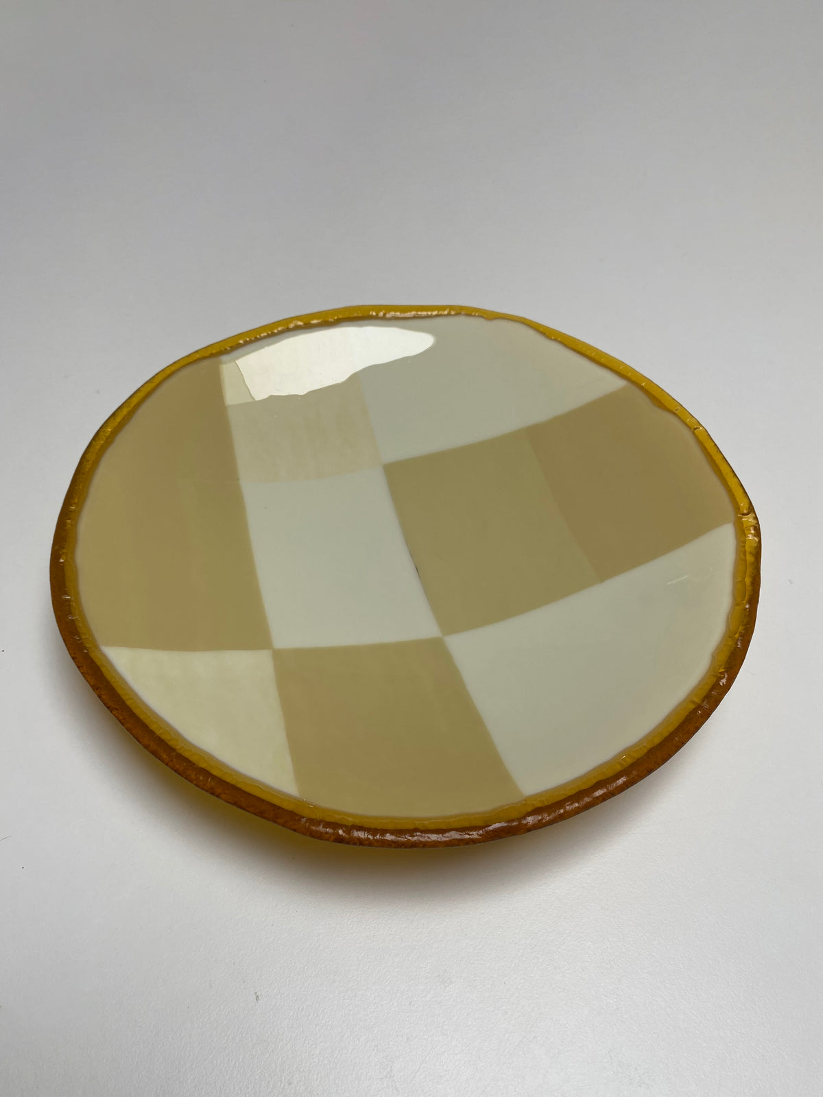 Beige checkered glass plate with amber rim, angled view