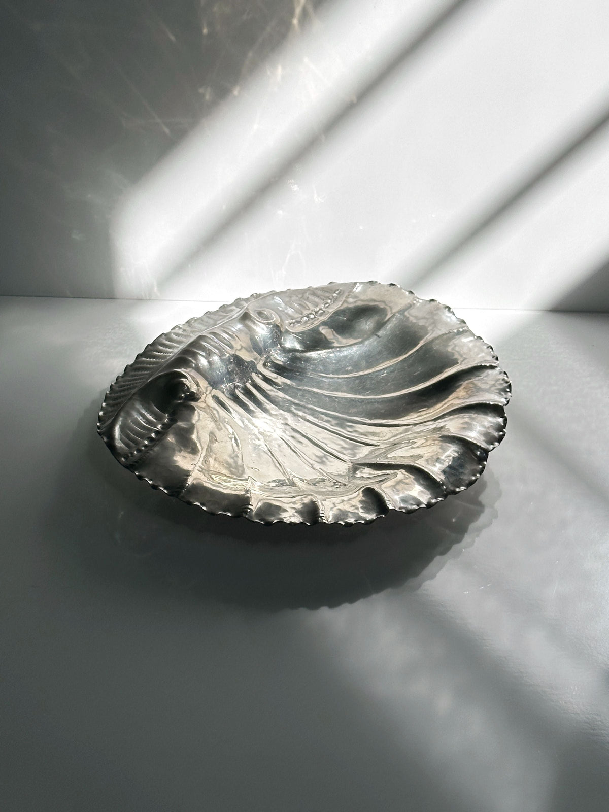 Handmade tin shell bowl detail showing curved ridges and scalloped edge