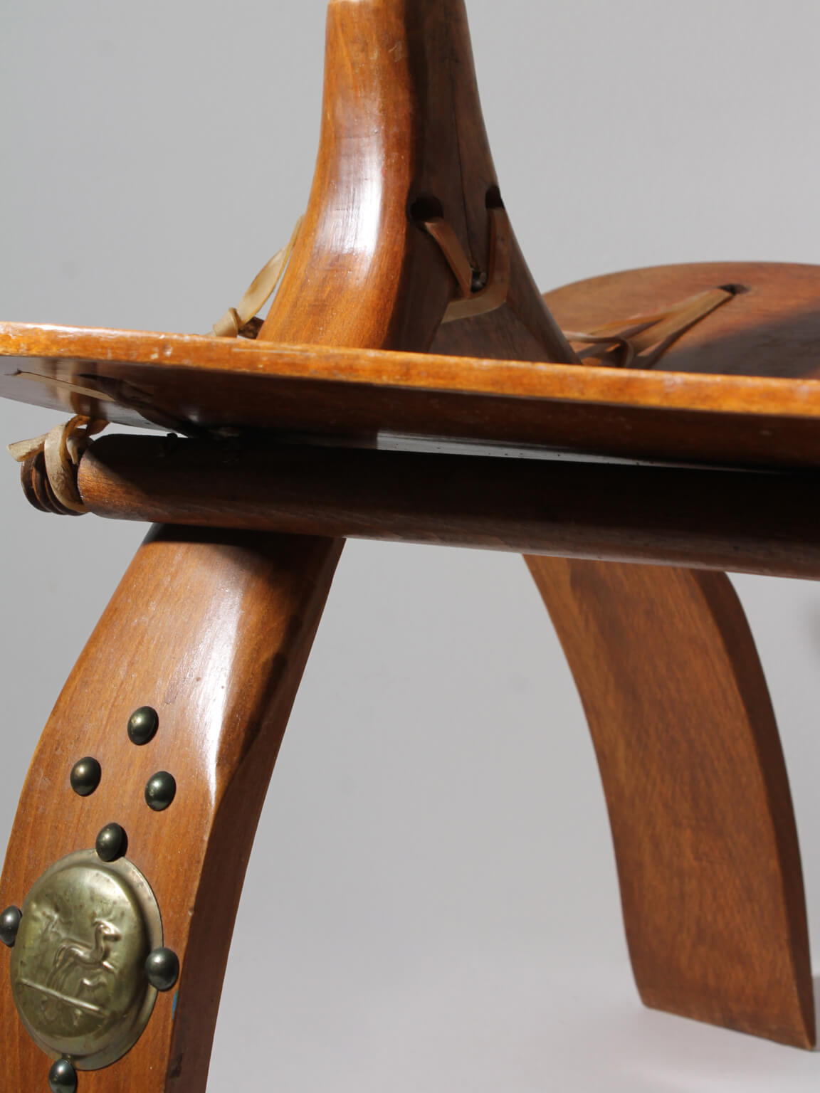 Egyptian Ottoman Camel Saddle Stool — angled view highlighting wooden legs and brass detail