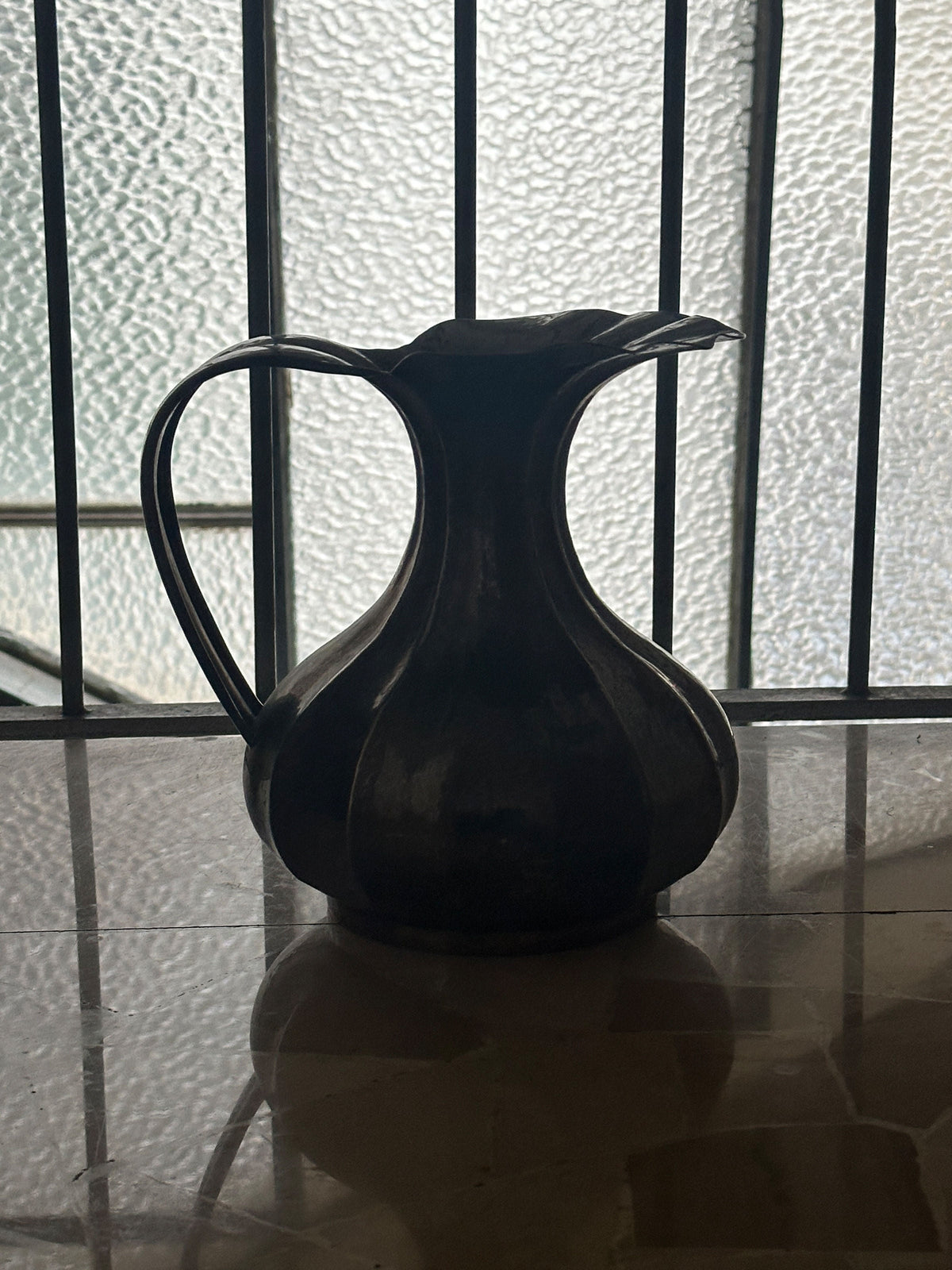 Dark silhouette profile of Art Nouveau metal vase with curved handle