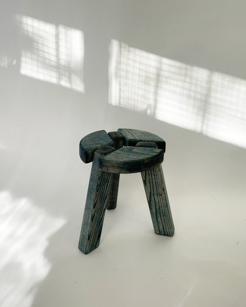 Dark green wooden stool with curved seat and thick legs