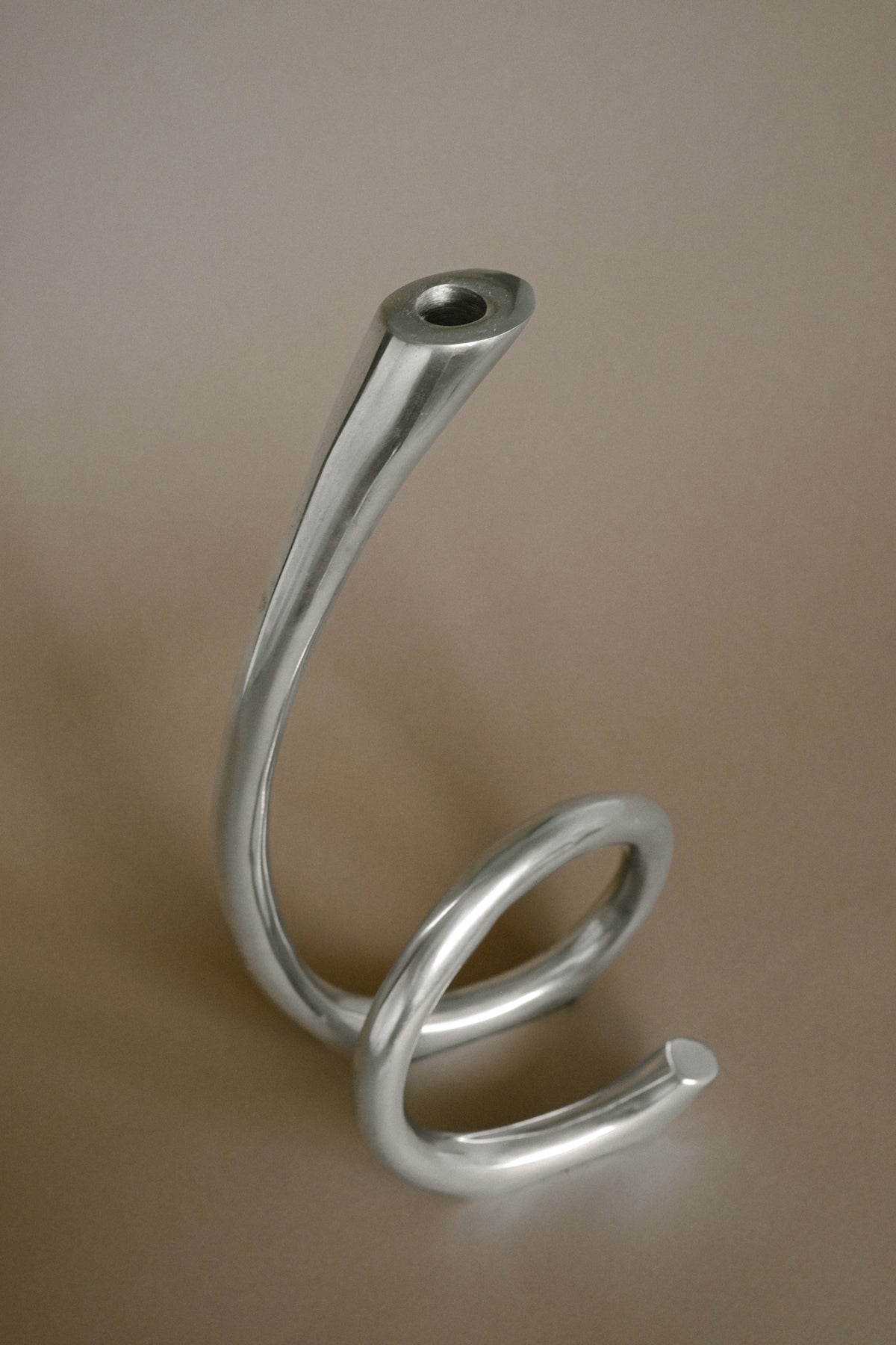Curved silver metal candleholder showing spiral base detail