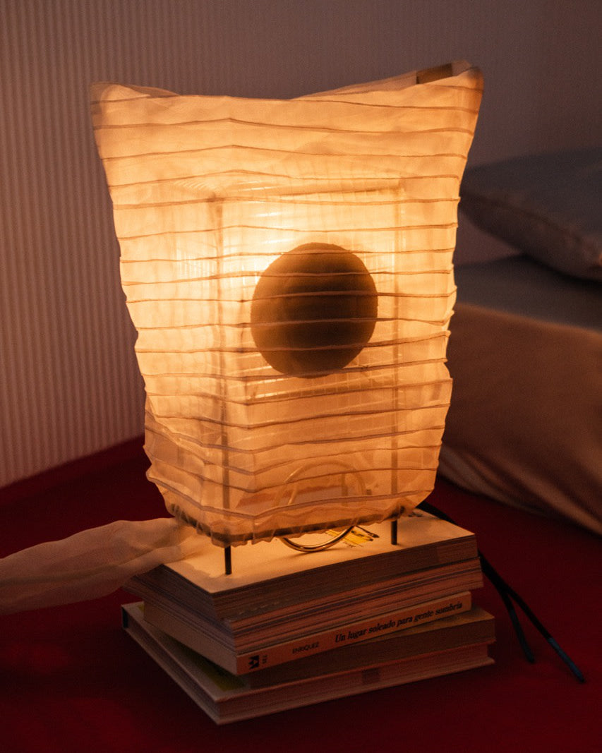 Illuminated paper lantern table lamp with dark circle accent on books