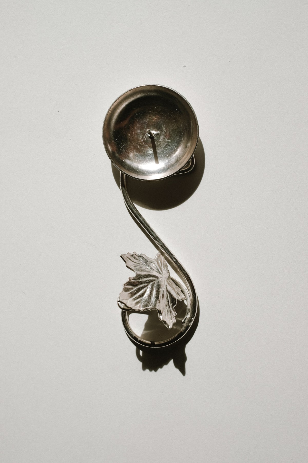 Curved silver-plated candle holder with decorative leaf detail