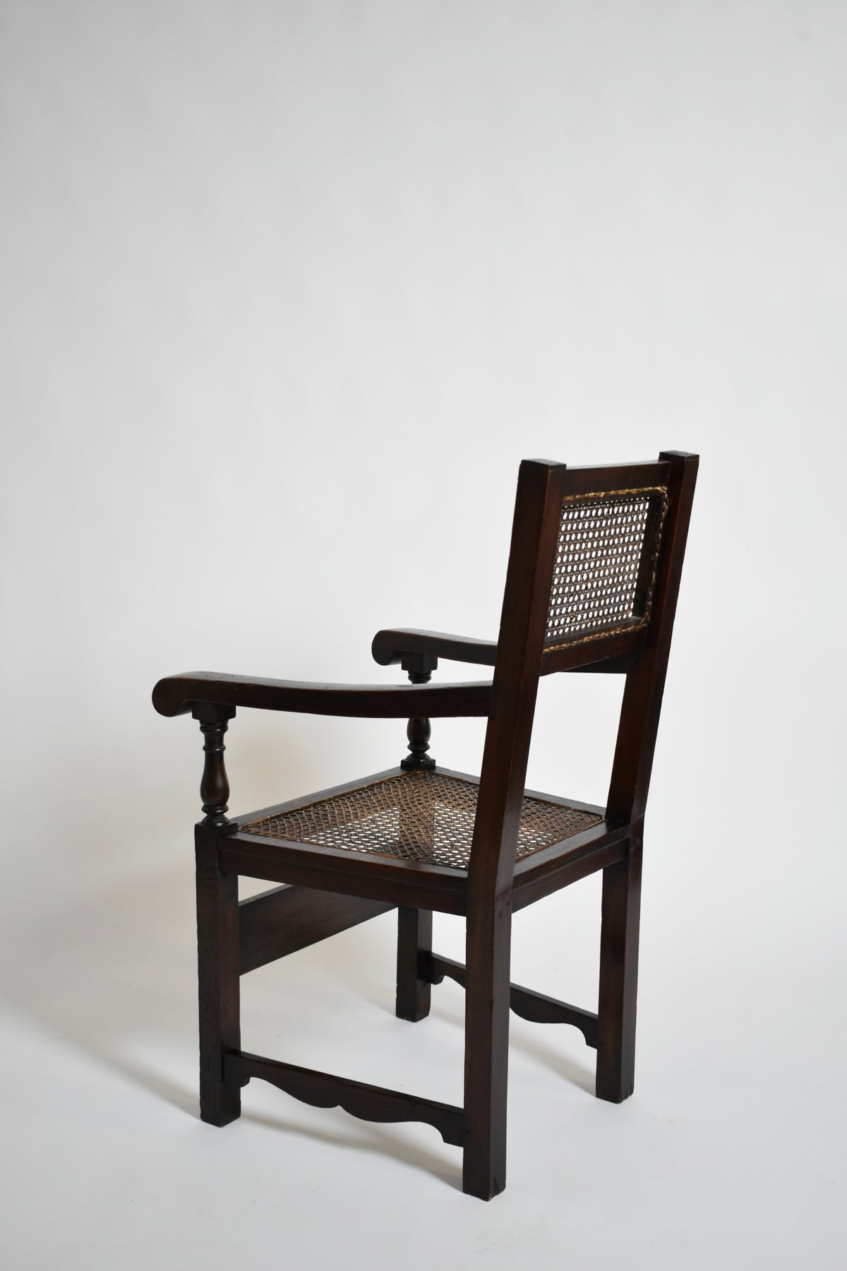 Pair of turned wood and cane armchairs, 1910s — angled view highlighting cane seat and wooden frame