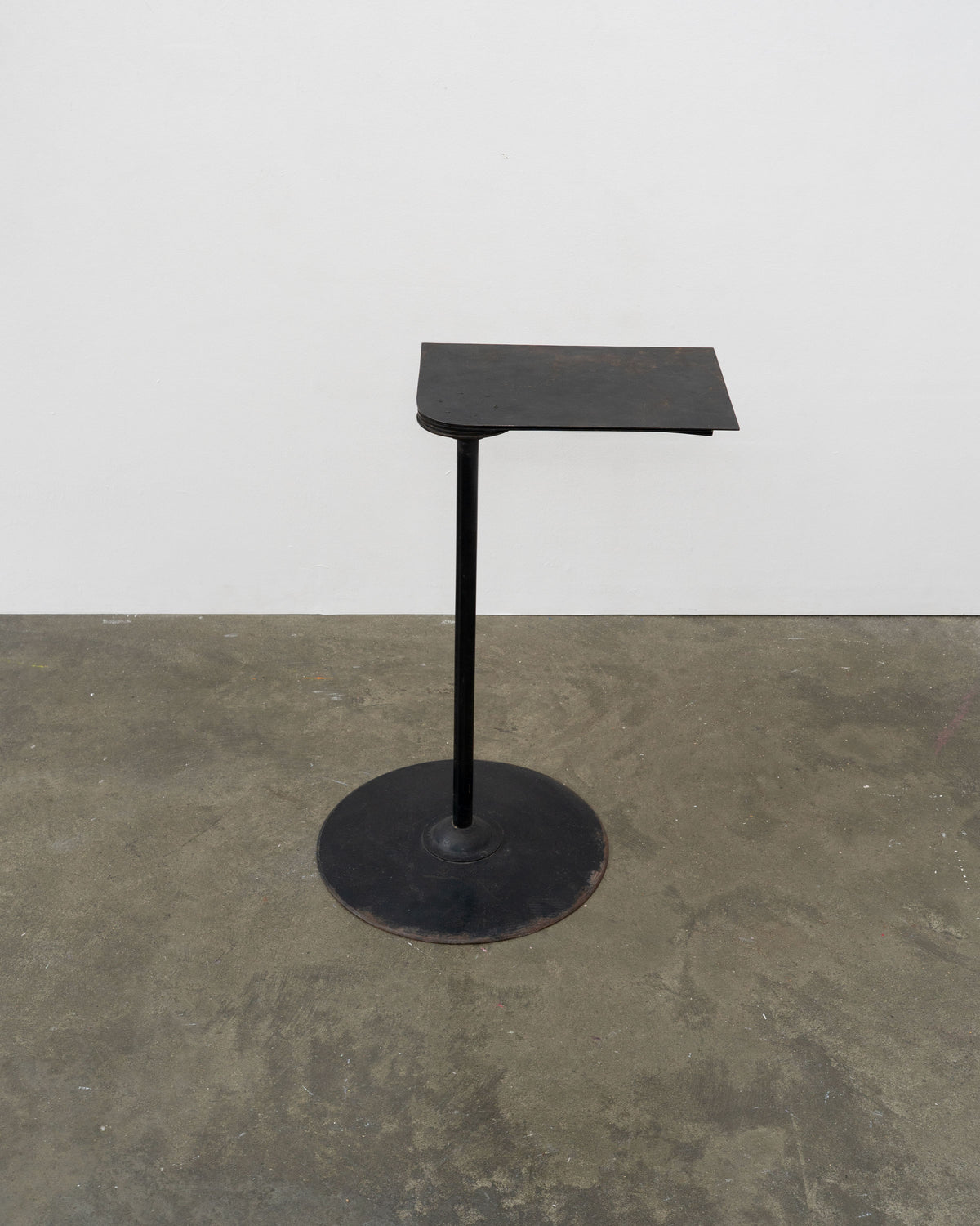 Black metal side table with tilted rectangular top and circular base by Pierre Chareau