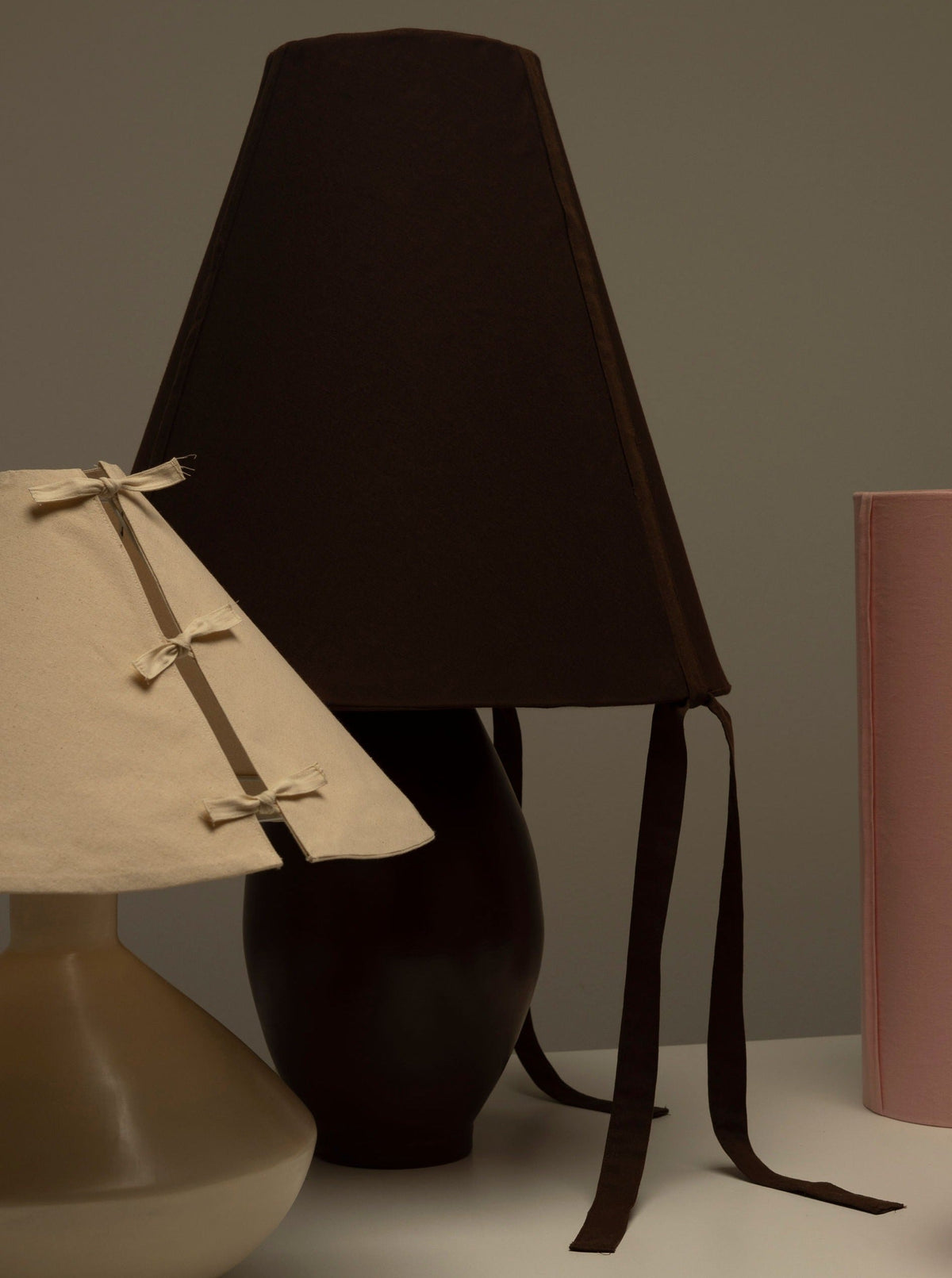 Brown ceramic large lamp with dark fabric shade and ribbon ties, styled with cream and pink lamps